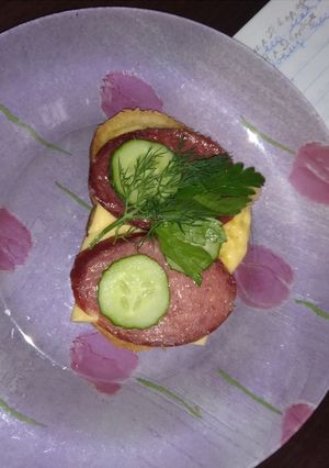 Бутерброд с расплавленным сыром, колбасой и огурцами